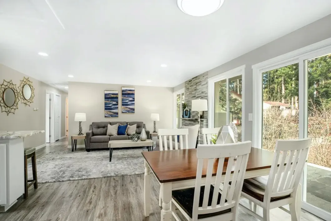 Dining area and living room with gray luxury vinyl plank flooring and a stone fireplace