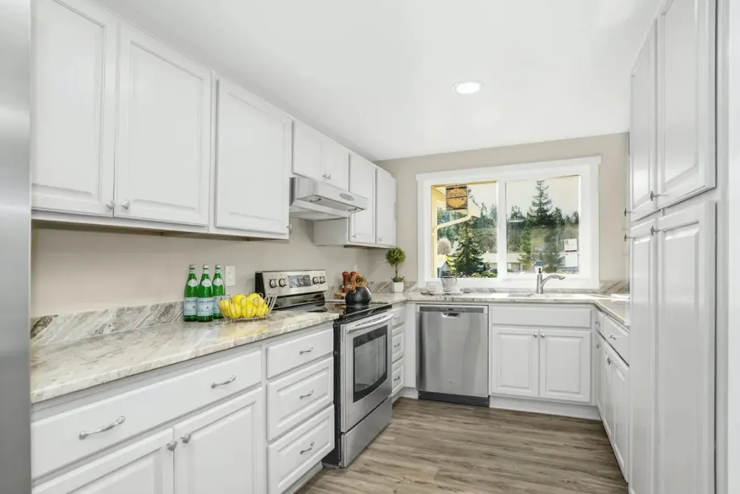 Remodeled kitchen with white cabinets, stone counters and stainless appliances