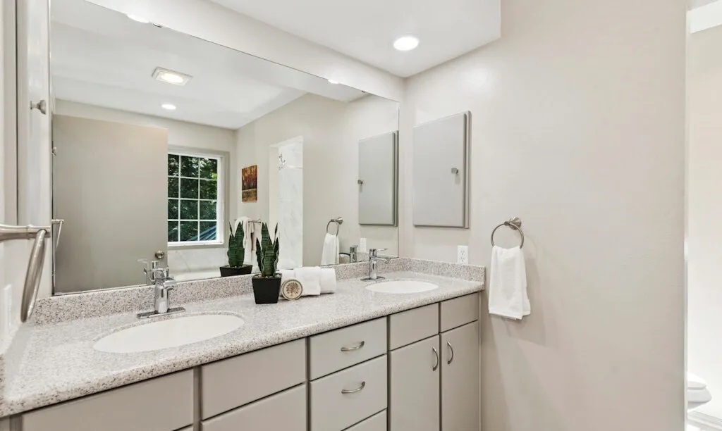 Remodeled bathroom with a double vanity, stone countertop and new lighting