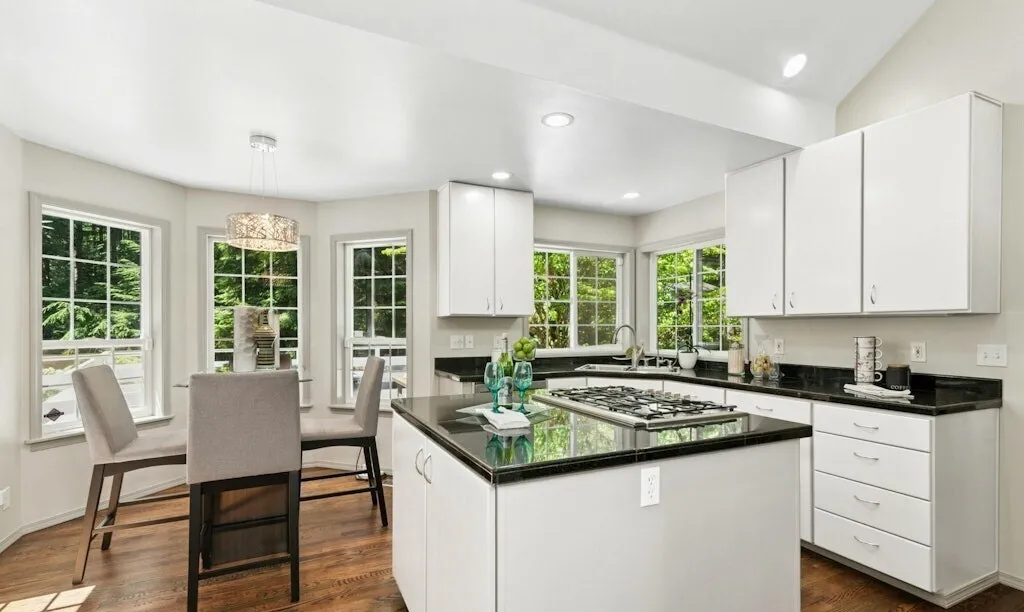 Kitchen with white cabinets, an island and dark stone countertops